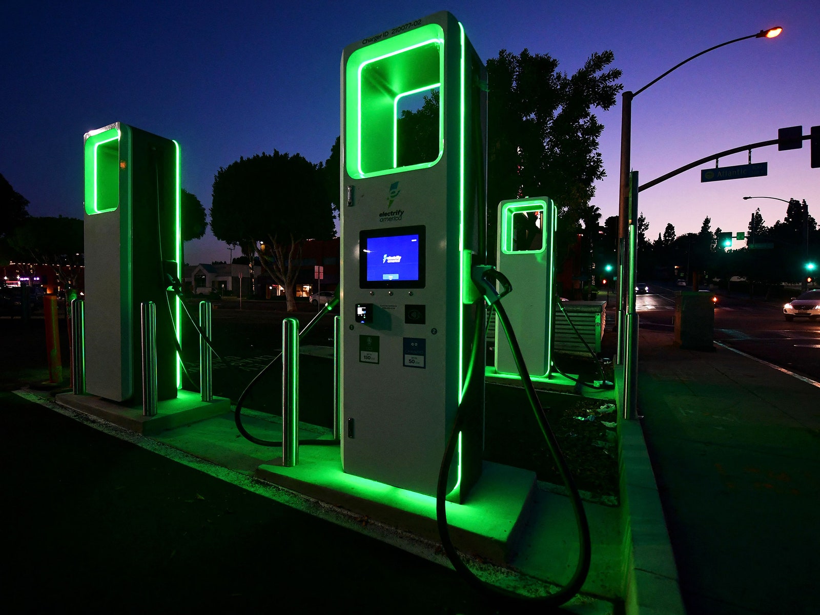 Electric car charging station in California lit up with neon green lights at dusk