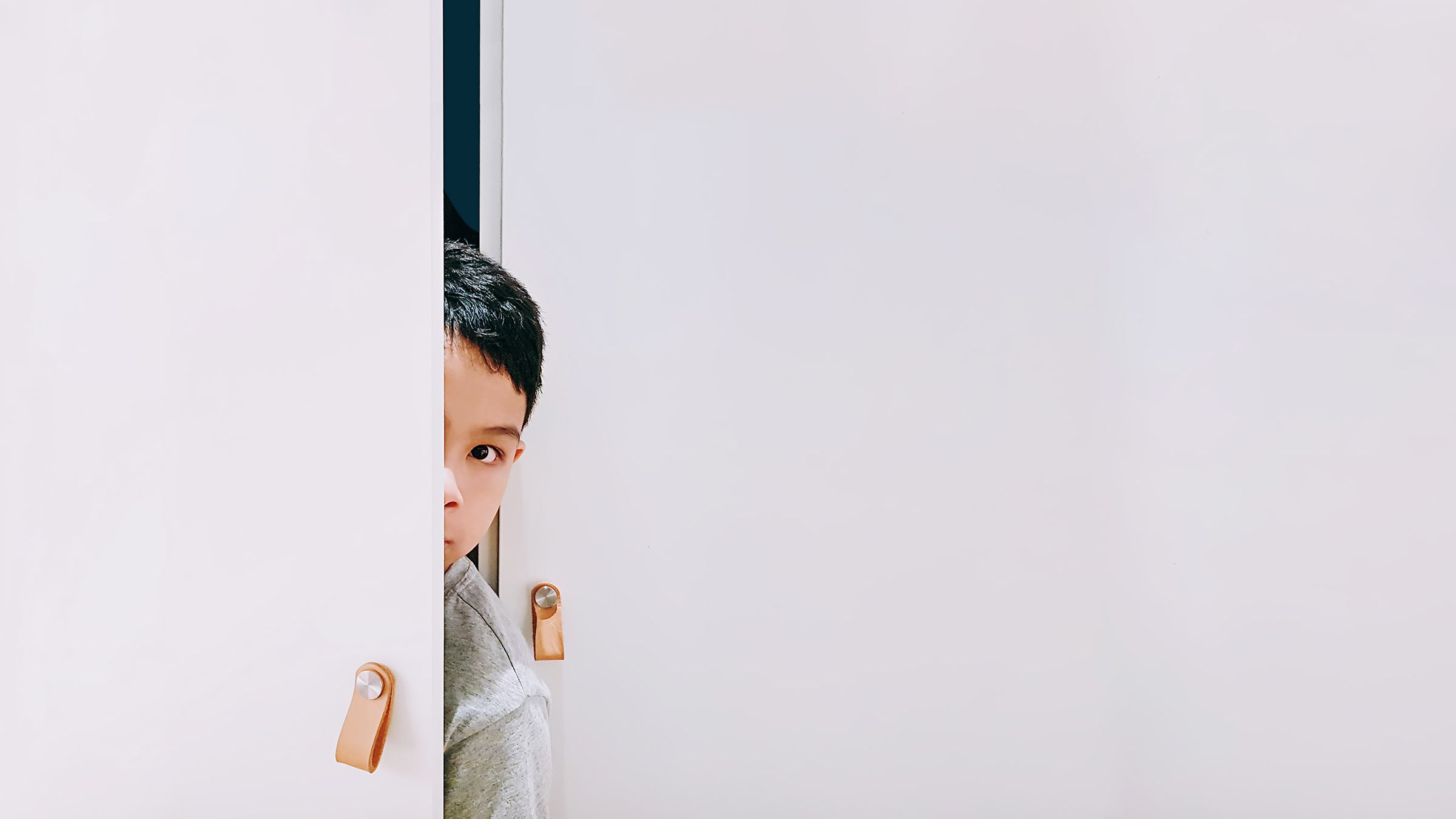 Child peeking through white doors