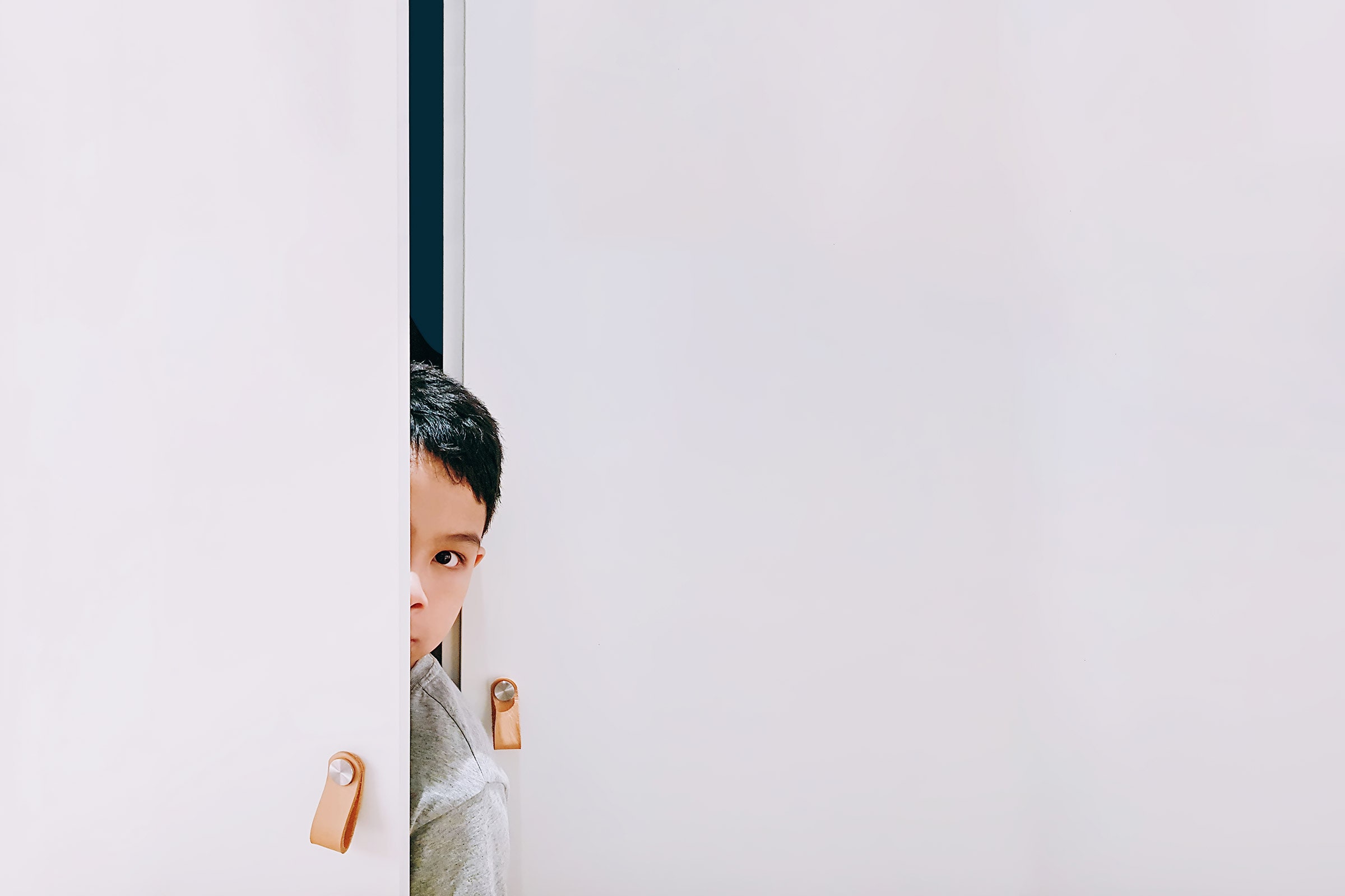 Child peeking through white doors