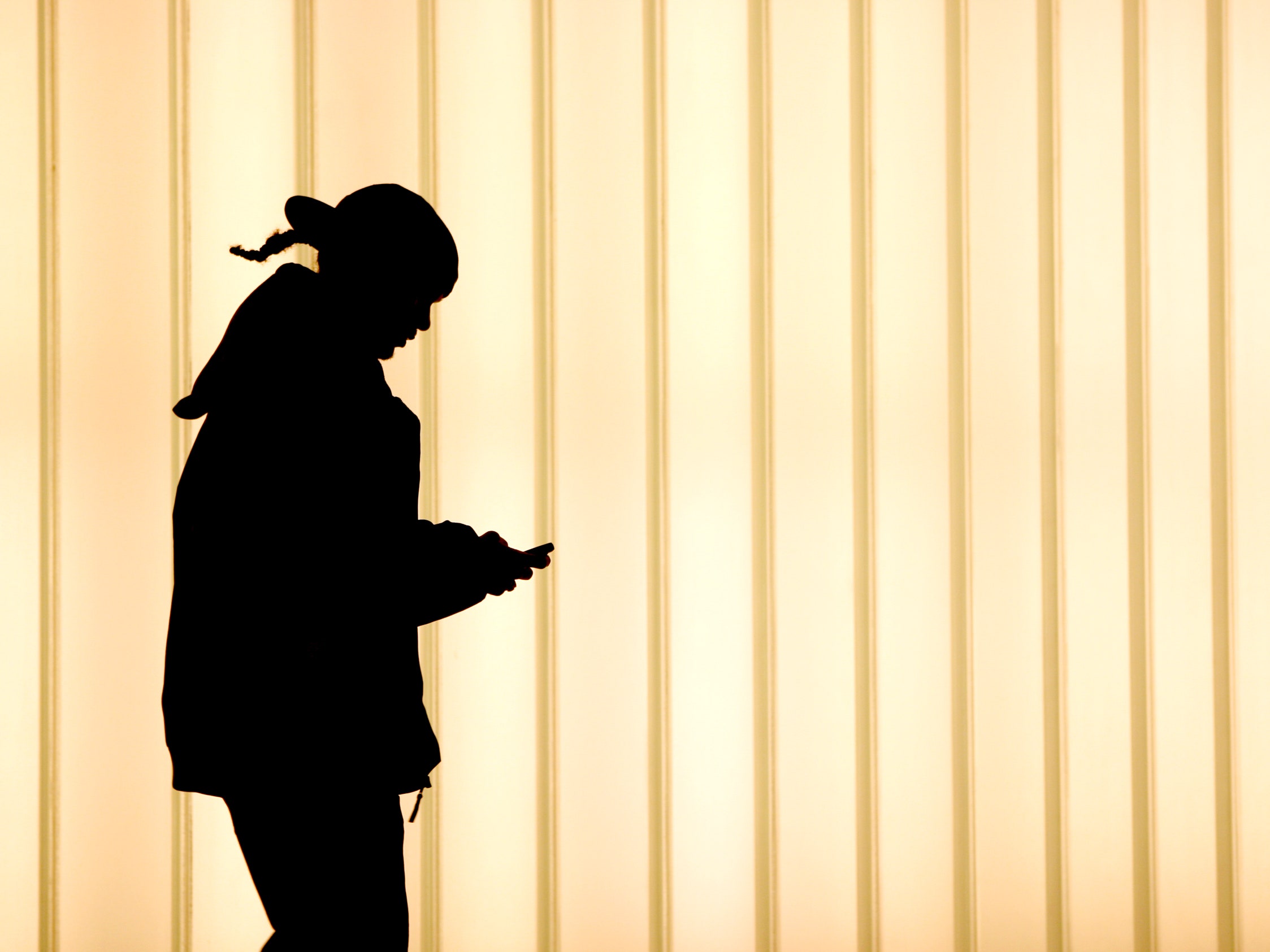 Silhouette of a woman walking and looking at smartphone